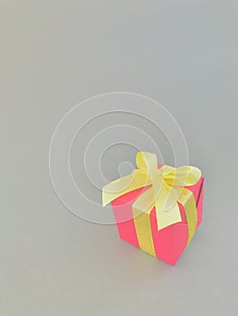 Red gift box with yellow ribbon on grey background. vertical.