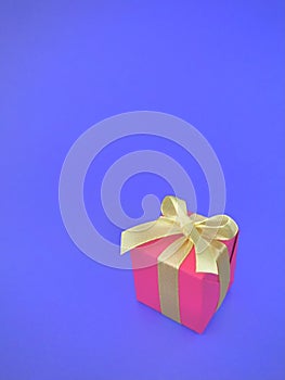 Red gift box with yellow ribbon on indigo background. vertical.