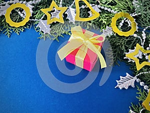 A red gift box with yellow ribbons bow on luxury blue background.