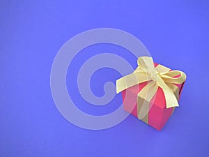 Red gift box with yellow ribbon on indigo background. copy space