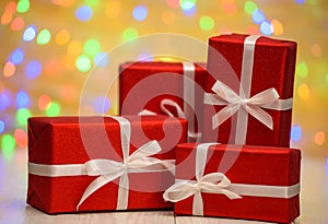 Red gift boxes with ribbon against golden bokeh background, free space. Holiday greeting card for birthday, wedding.