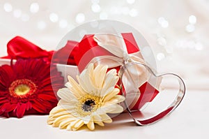 Red gift boxes with ribbons and flowers on a white delicate background with bokeh