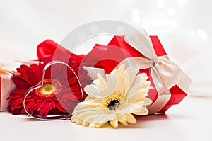 Red gift boxes with ribbons, heart and flowers on a white delicate background with bokeh