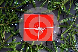 Red gift paper, box with silver ribbon, led garland and fir tree branches around