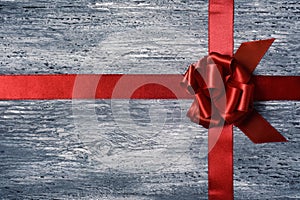 Red gift ribbon bow on a wooden surface