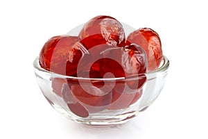 Red glace cherries in glass bowl isolated on white.