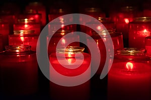 Red glass candles lit in a dark church