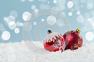 Red glass Christmas balls in the snow on a blue background with bokeh lights. happy new year card