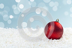 Red glass Christmas balls in the snow on a blue background with bokeh lights. happy new year card