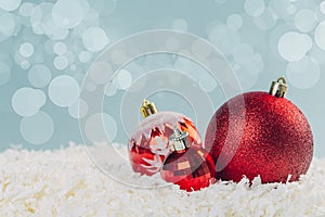 Red glass Christmas balls in the snow on a blue background with bokeh lights. happy new year card