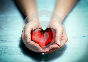 Red glass heart in woman hands