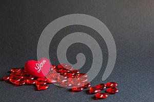 Red glass hearts and a soft plush heart with the words Love on a black background - Valentine`s day. Holiday, banner, copyspace.