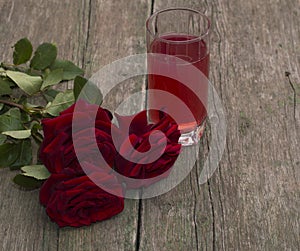 Red glass of juice and bouquet of red roses