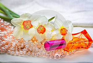 Red glass perfume bottle, pearl beads and daffodil flowers