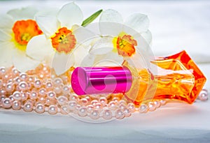 Red glass perfume bottle, pearl beads and daffodil flowers