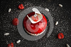 Red glazed cake decorated with white chocolate and raspberry