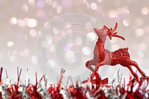 Red glitter reindeer ornament on white snow with abstract background