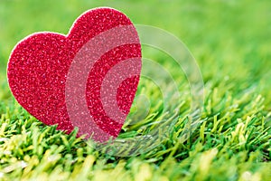 Red glittering heart in green lawn