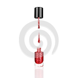 Red glittering nail polish glass bottle, brush & drop white background isolated closeup, open pink sequin varnish, scarlet lacquer