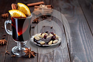 Red glogg or mulled wine with orange slices and cinnamon stick on dark wooden background, horizontal, copy space