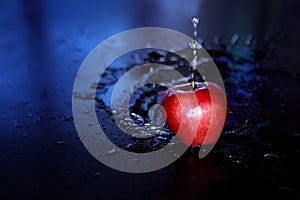 Red glossy Apple with water drops on a black background. Fresh and tasty food concept. Red apple with water droplet on glossy