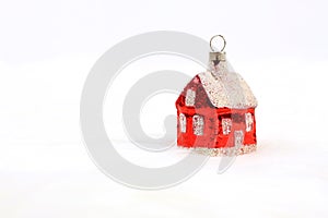 Red glossy Christmas decoration - little house standing on white fur background