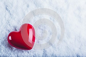 Red glossy heart on a frosty white snow background. Love and St. Valentine concept.