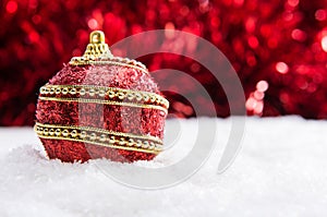 Red and gold Christmas ball in snow with tinsel, christmas background