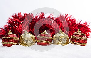 Red and gold Christmas balls in snow with tinsel and snowflakes, christmas background