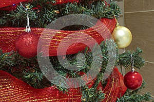 Red and gold christmas baubles with ribbon in a tree