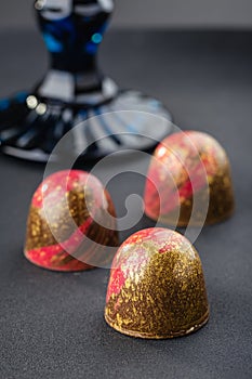 Handmade candy with red and gold splashes on black background. E