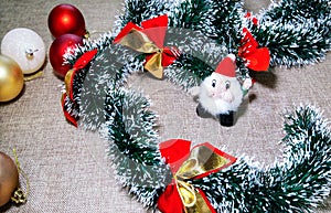 Red gold ribbons Christmas garland, baubles and Santa Claus toy.