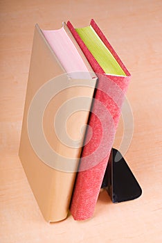 Red and golden books leaning on bookend