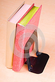 Red and golden books leaning on bookend