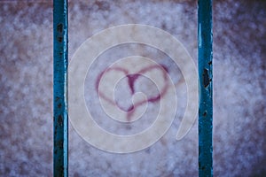 Red graffiti heart. Rusting fence.