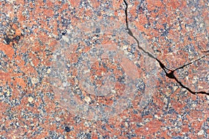 Red granite slab with a deep crack close-up. Texture of natural stone