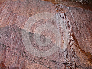 Red granite surface by flowing water over it.