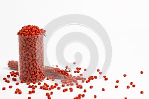 Red granules of polypropylene, polyamide in a measuring beaker and a test tube on a white background. Chemical products. Plastic,