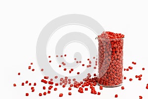 Red granules of polypropylene, polyamide in a measuring beaker and a test tube on a white background. Chemical products. Plastic,