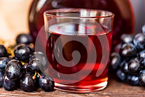 Red grape juice in glass and grapes close