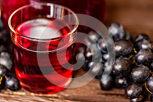Red grape juice in glass and grapes close