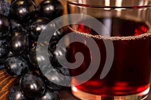 Red grape juice in glass and grapes close