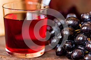 Red grape juice in glass and grapes close