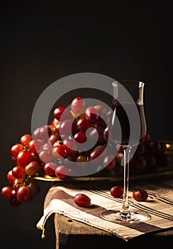 Red grape wine on wooden table and black background. home made nature wine with fresh red grapes.