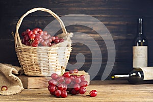 Red grapes with a bunch of grapes in a sweet natural fruit wooden basket with a wine bottle Placed on the table, black and dark