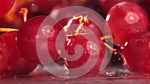 Red grapes fall with splashes on a wet table. Filmed on a high-speed camera at 1000 fps.