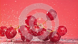 Red grapes fall with splashes on a wet table. Filmed on a high-speed camera at 1000 fps.