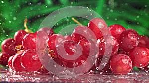 Red grapes fall with splashes on a wet table. Filmed on a high-speed camera at 1000 fps.