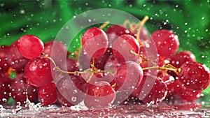 Red grapes fall with splashes on a wet table. Filmed on a high-speed camera at 1000 fps.