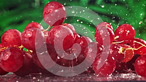 Red grapes fall with splashes on a wet table. Filmed on a high-speed camera at 1000 fps.